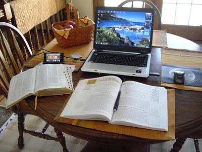 Round dining room table with open laptop computer, bible, study books, and a basket of apples.